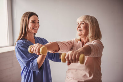 woman helping senior in her daily exercise