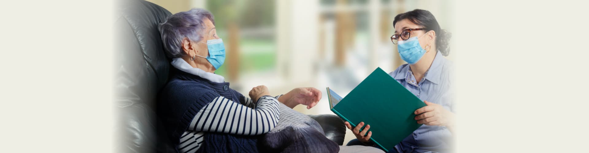 female caregiver reads books for an elderly woman